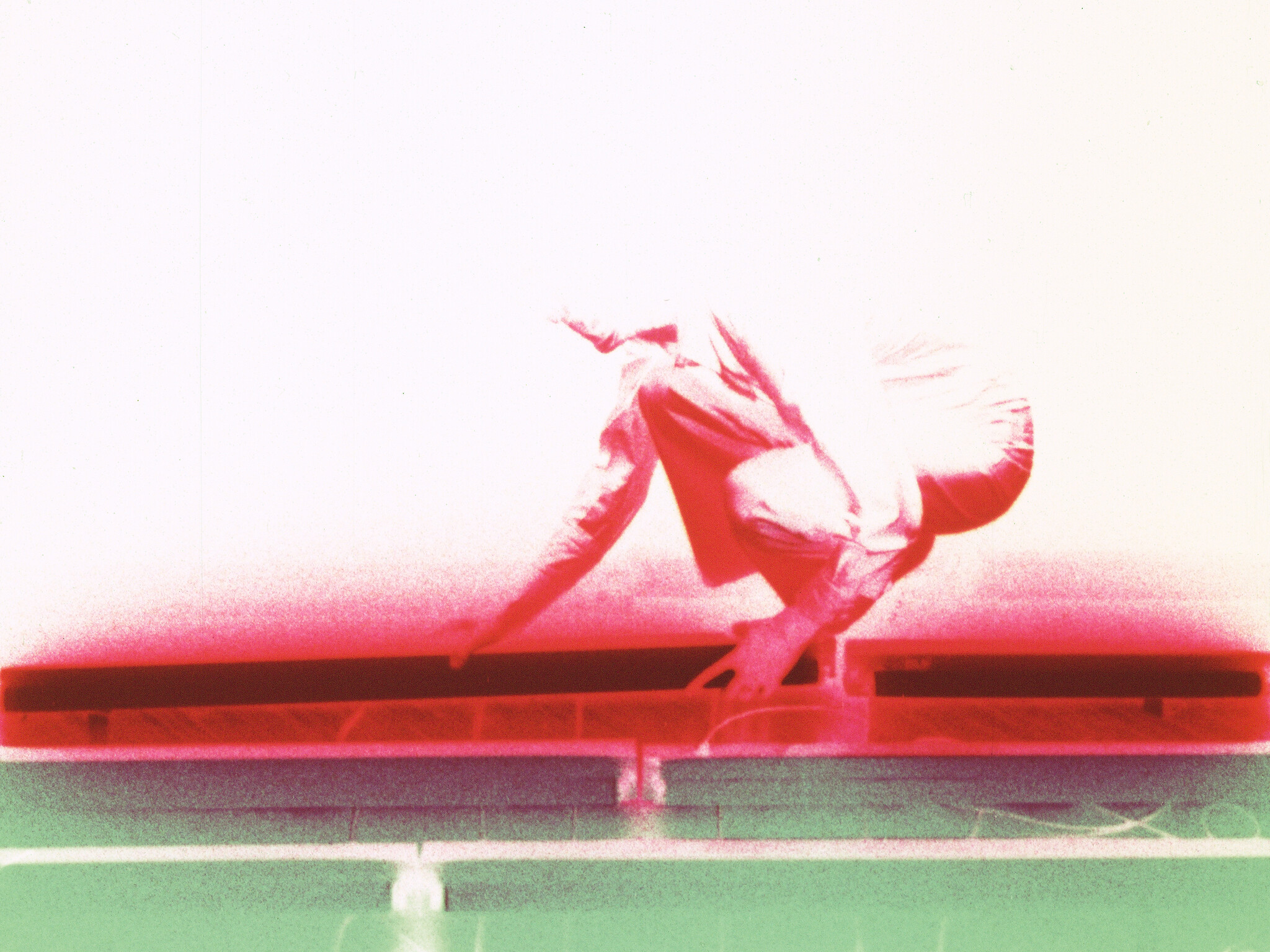 Person in a crouched position reaching forward, with bright red and green lighting effects in the background.