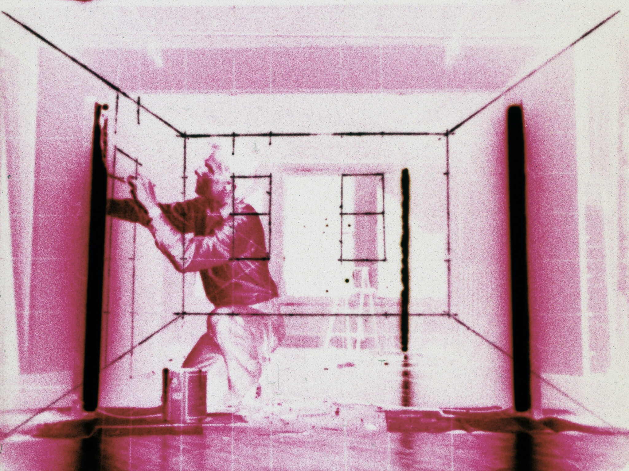 Person kneeling and drawing lines on a wall inside a room, with a grid pattern overlay on the image.
