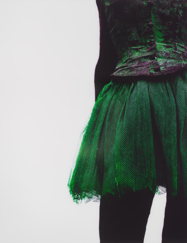 A person wearing a green tulle skirt and dark corset shown from the waist down.
