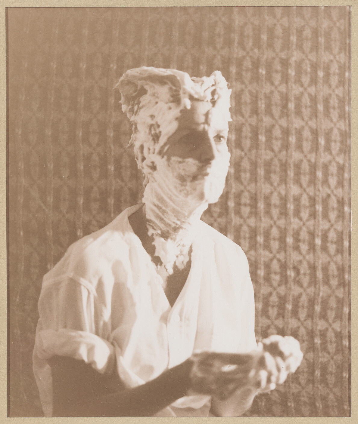 Man with his face and head covered in shaving cream holding a bowl of foam.