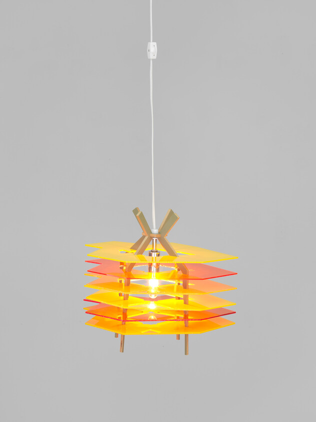 A hanging pendant lamp with stacked yellow and orange panels glowing from a white cord.