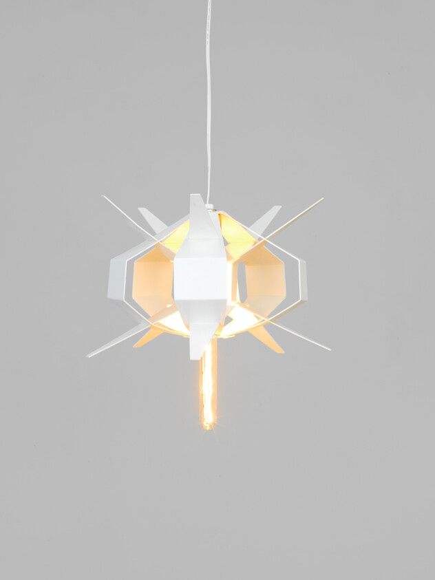 A modern geometric white pendant light hangs with a glowing exposed filament bulb.