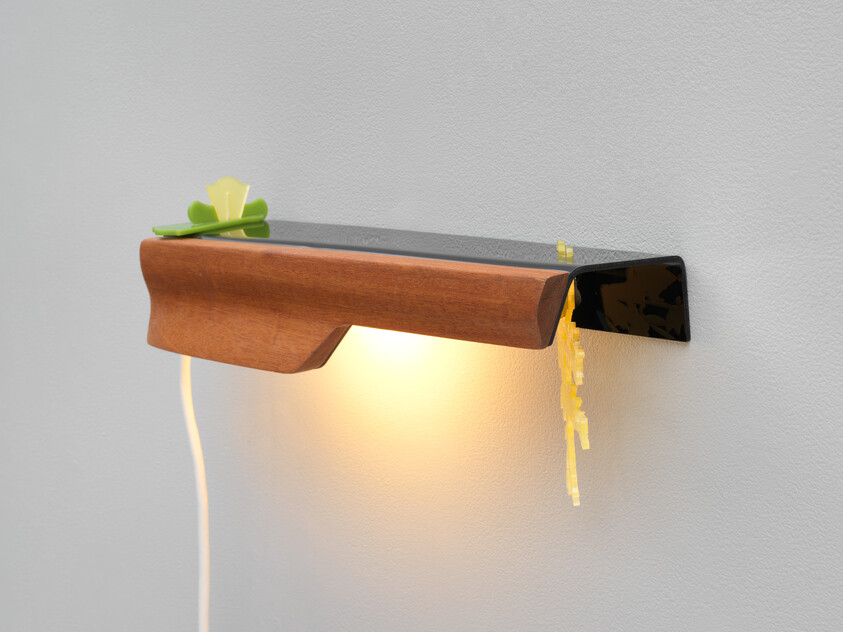 A wall-mounted wooden shelf with an integrated warm light, a green decoration, and a hanging cord.