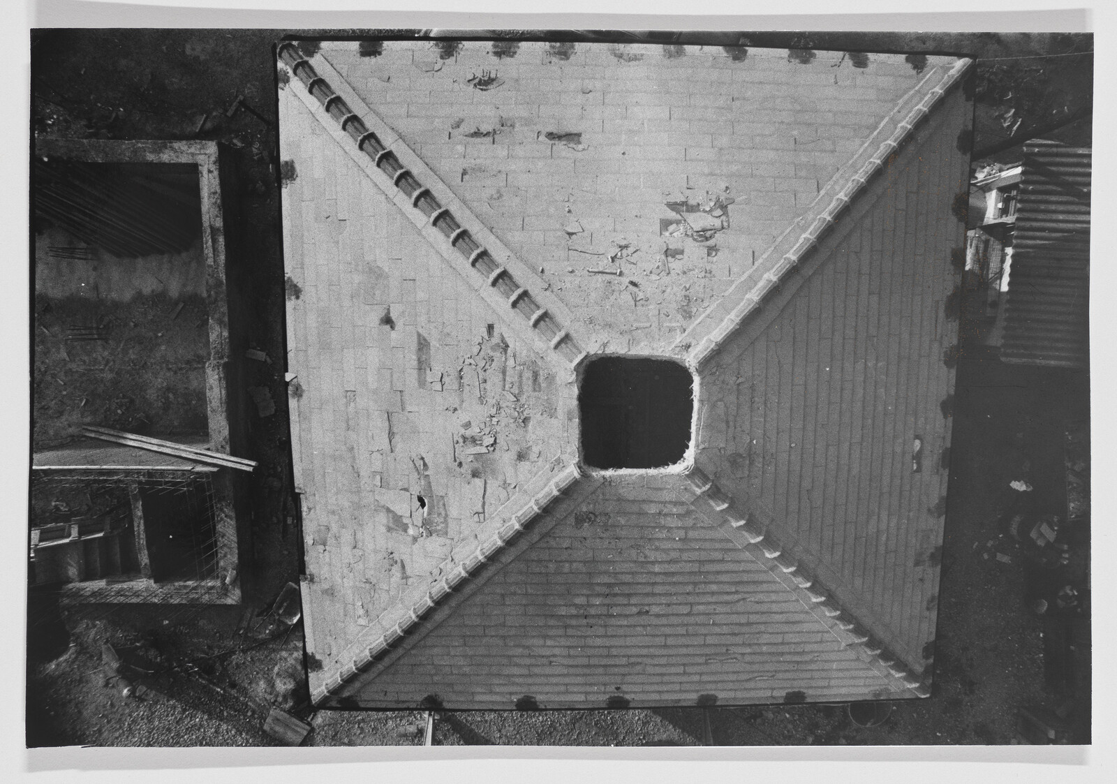 Square tiled roof with a large central square opening and peeling shingles.