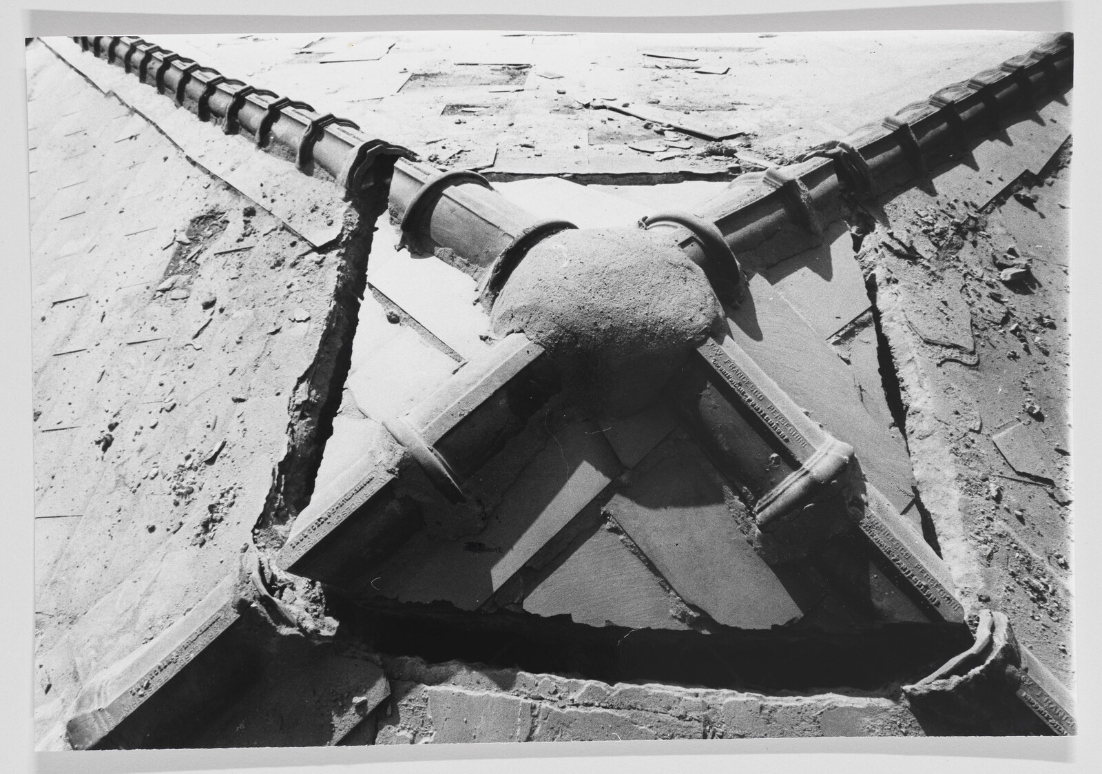 Three ridge tiles meet at a triangular roof junction with cracked mortar and broken shingles.