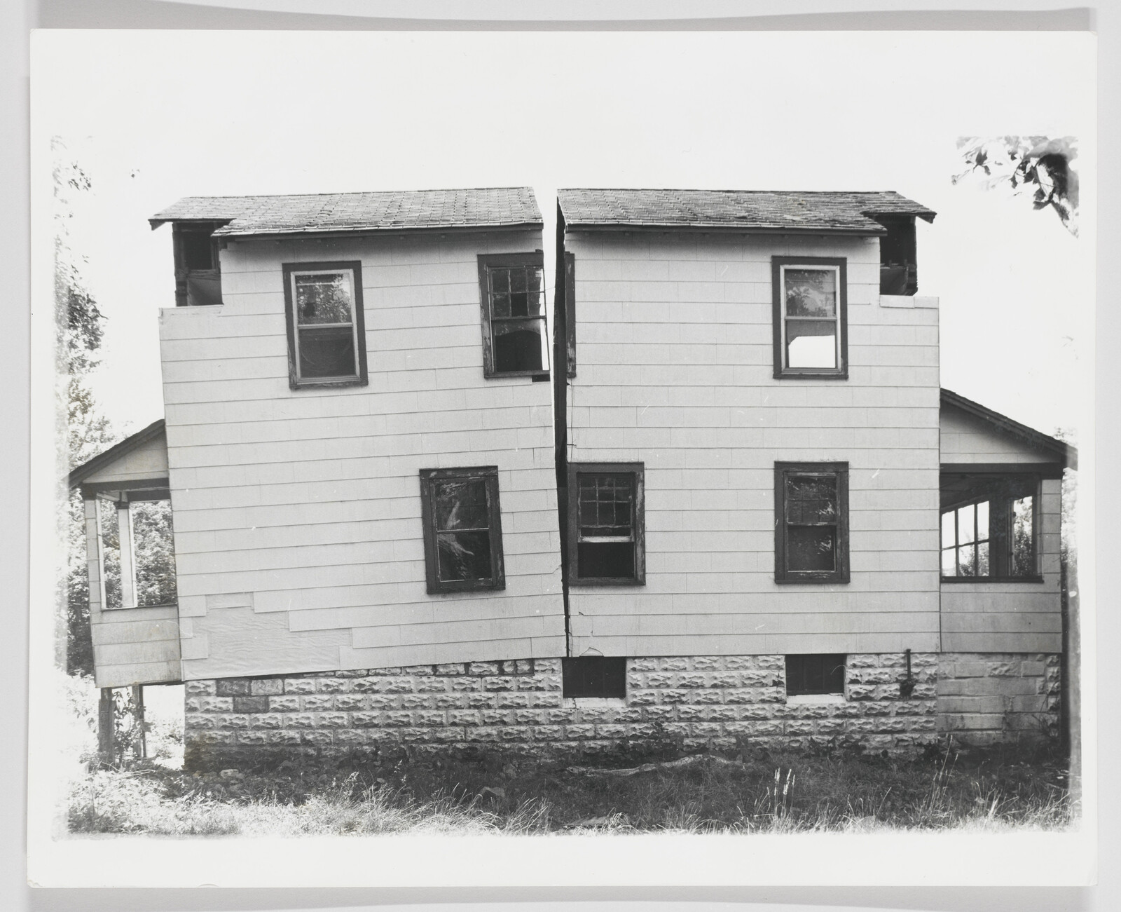 Two-story house split vertically down the middle with a visible gap between mirrored halves.