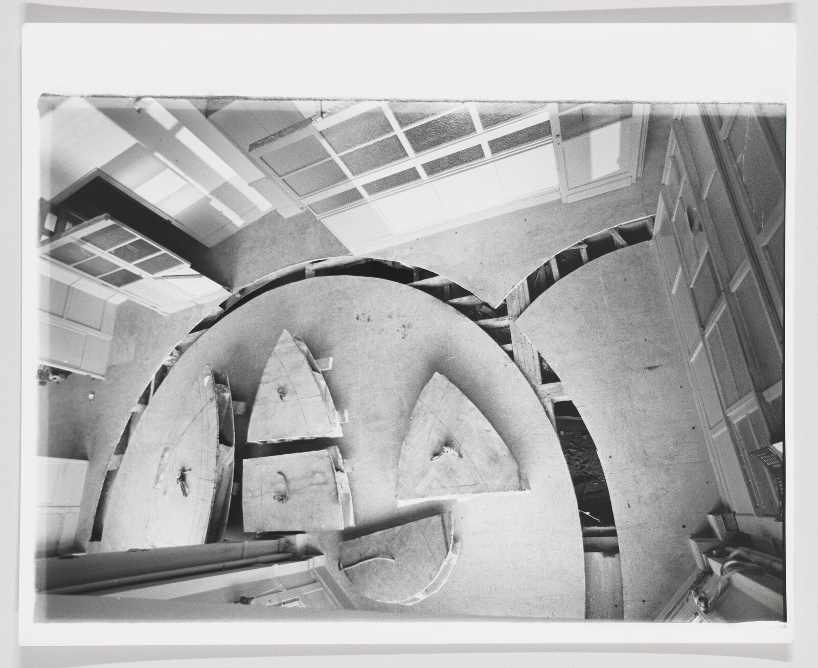 Circular sections of a wooden floor are cut away, exposing joists and triangular removed panels.