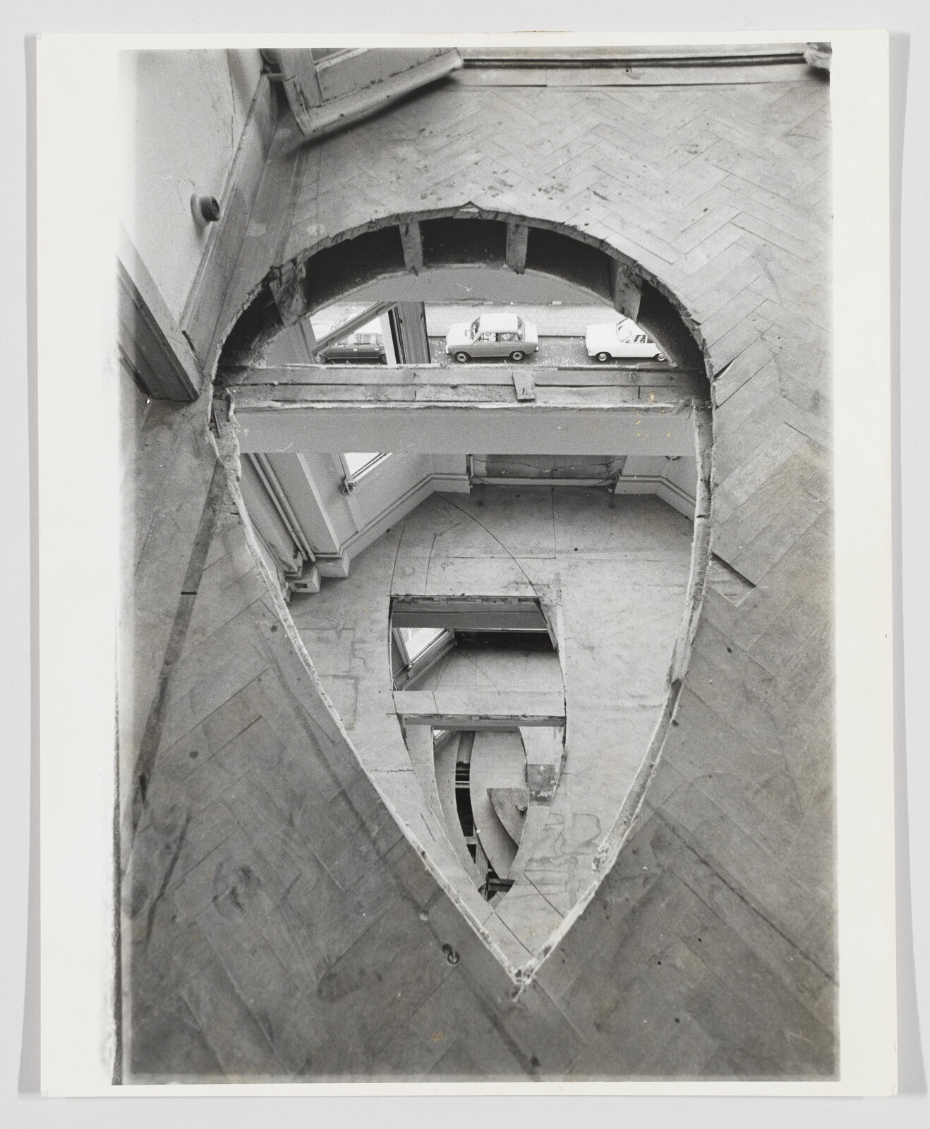 Large teardrop-shaped holes cut through multiple wooden floors revealing lower rooms and a street view.