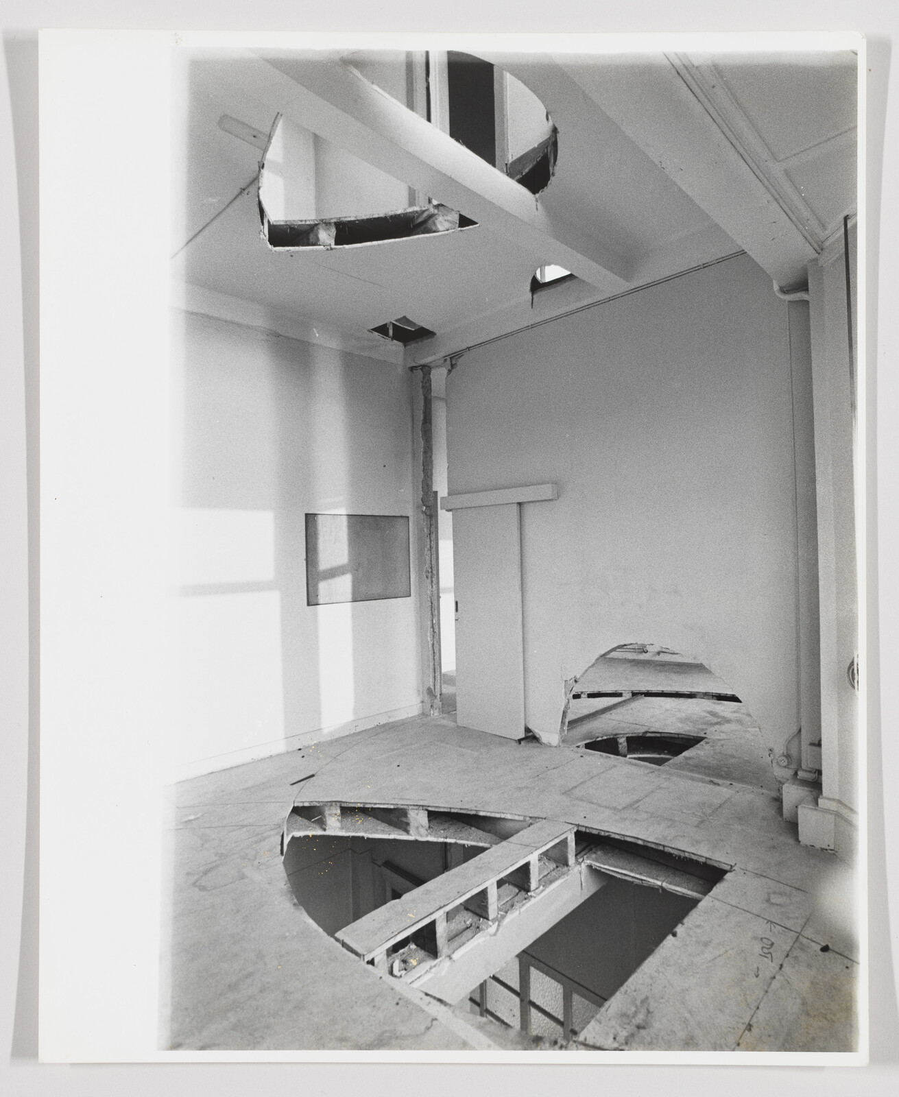 Room with large circular holes cut into the floor and ceiling exposing the space below.