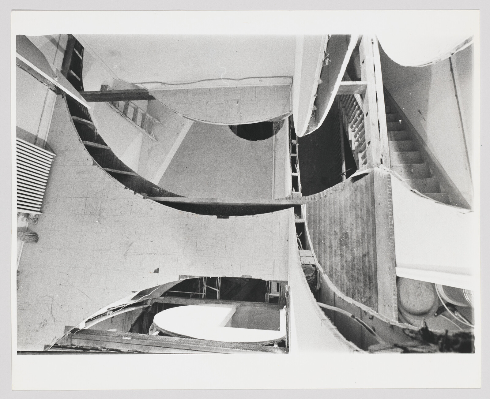 Interior walls partially demolished revealing curved cutouts, exposed studs, and a stairwell.