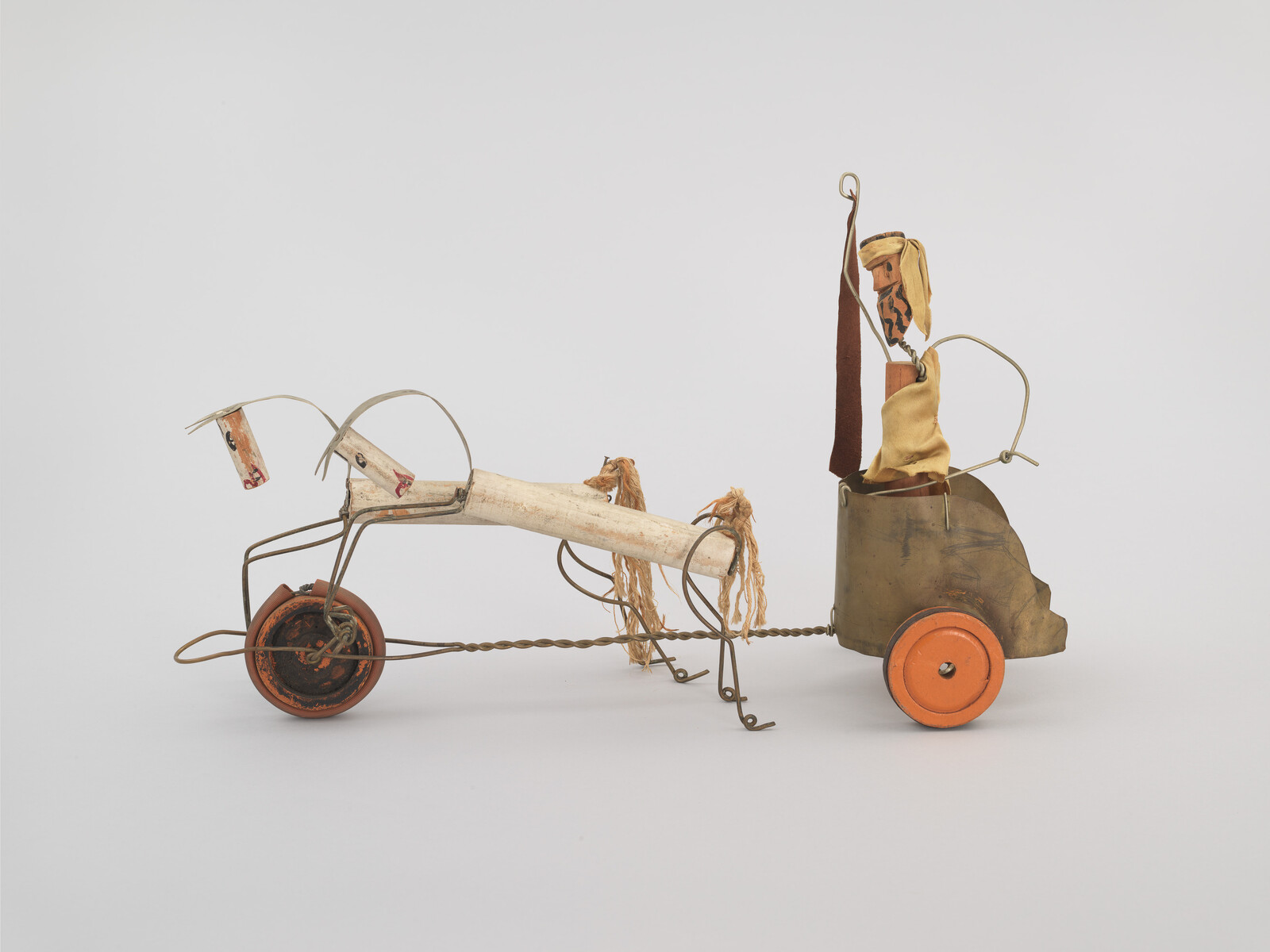 A handmade toy chariot pulled by a wooden horse figure made from wire, cloth, and wheels.