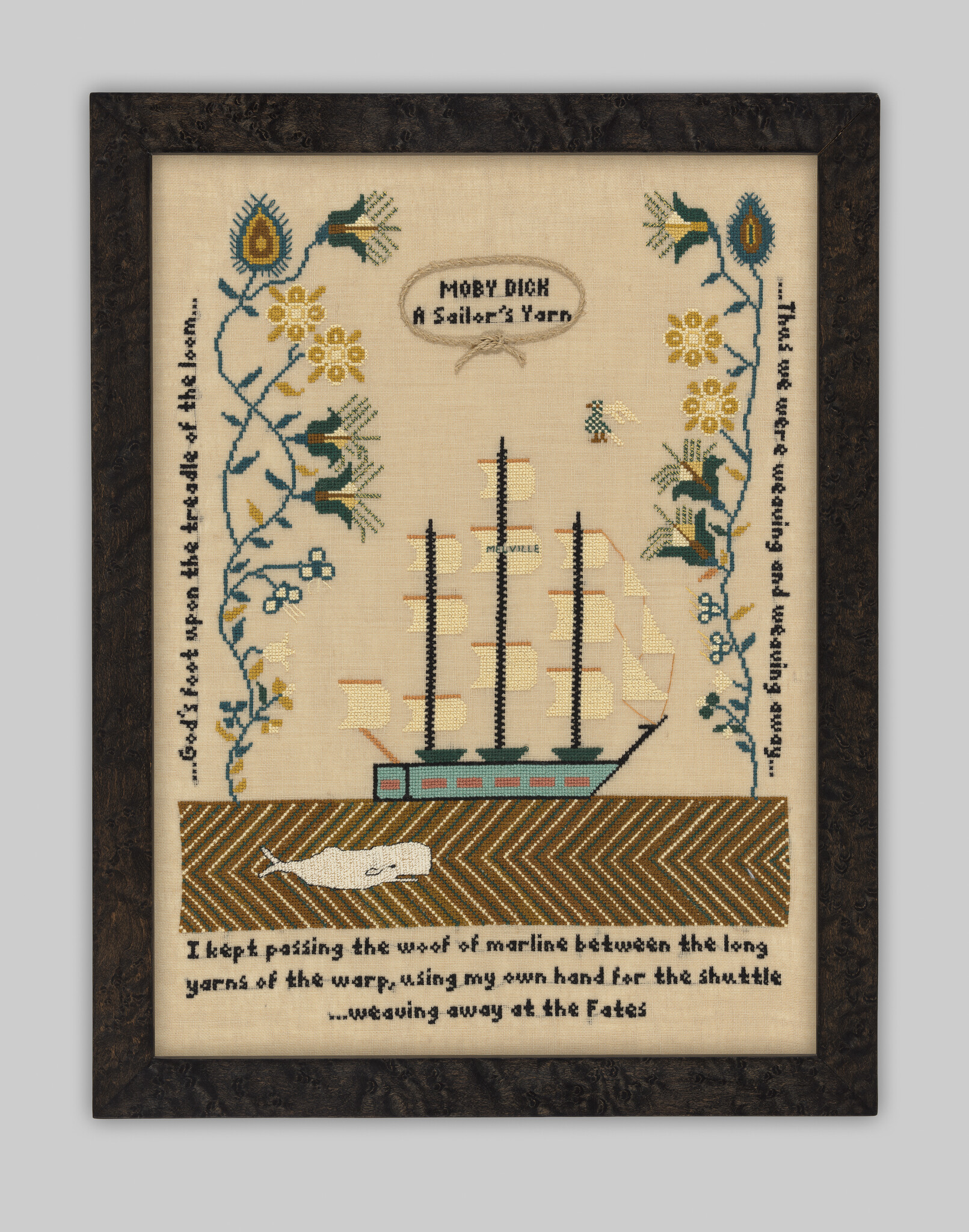 Framed embroidered sampler showing a sailing ship, a white whale, and the title "Moby Dick: A Sailor's Yarn."