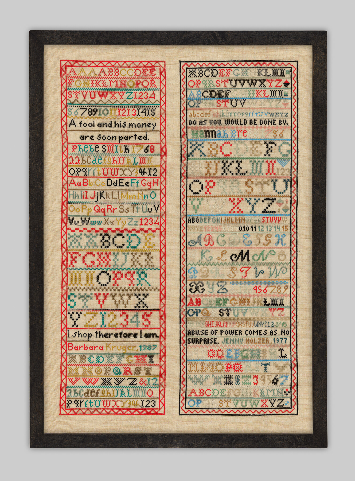 Framed artwork resembling a traditional sampler with two columns of cross-stitched text and symbols. The left column features alphabets in upper and lower case, numbers, and phrases like "A fool and his money are soon parted." The right column includes similar elements with the phrase "Do as you would be done by." Both columns contain references to artists Barbara Kruger and Jenny Holzer with dates 1987 and 1977 respectively. The piece combines elements of folk art with modern conceptual art references.
