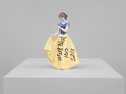 A porcelain Snow White figurine stands on a pedestal with black handwriting and dates on her skirt.