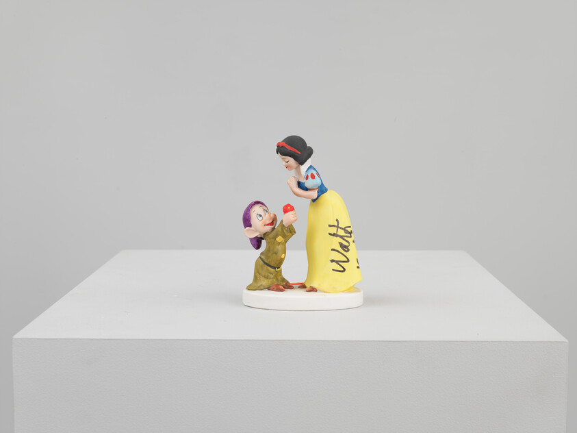 Snow White leans forward as a dwarf offers her a red apple on a display pedestal.
