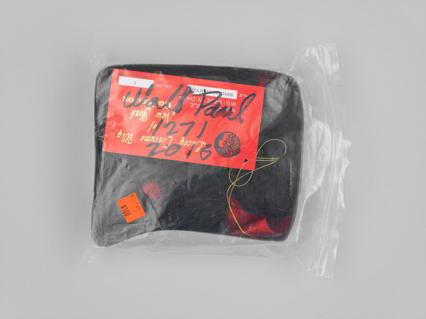 A black vinyl pouch sealed in a clear plastic bag with a red handwritten label.
