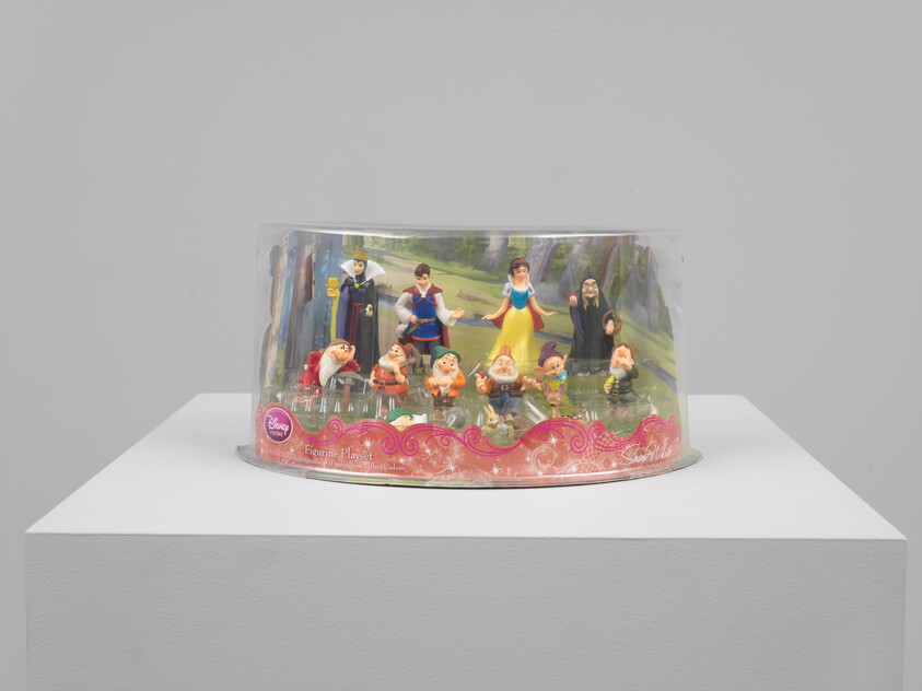 Packaged Snow White and the Seven Dwarfs figurine playset displayed on a white pedestal.