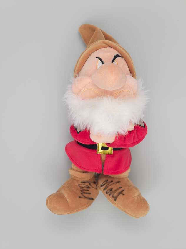 Plush grumpy dwarf wearing red coat and brown hat with white beard and signed boots.