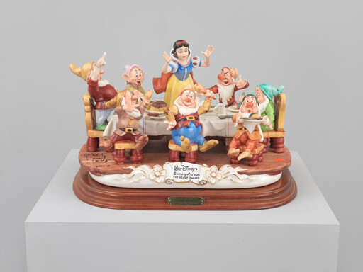 Snow White stands behind a table as the seven dwarfs eat, cheer, and pose around her.
