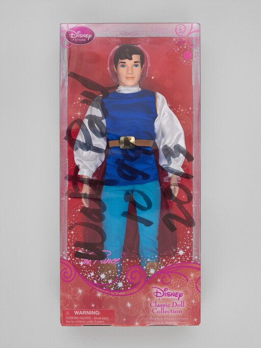 A Disney classic prince doll in original pink boxed packaging with black marker scribbles across the front.