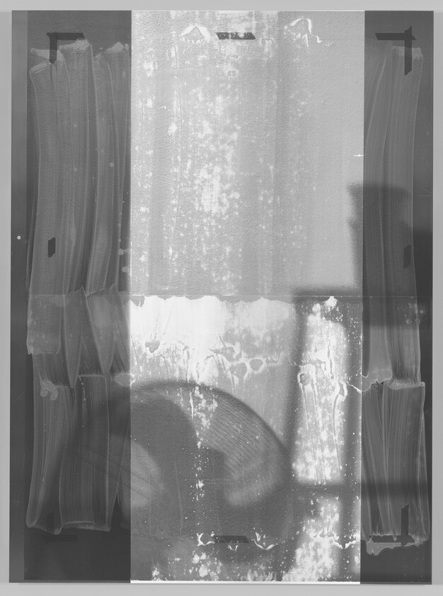 Old X-ray film with vertical streaks and a large circular shadow near the bottom center.