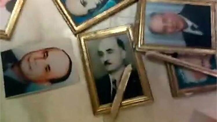Several framed portraits of people are lying on the floor, with some frames broken or damaged.