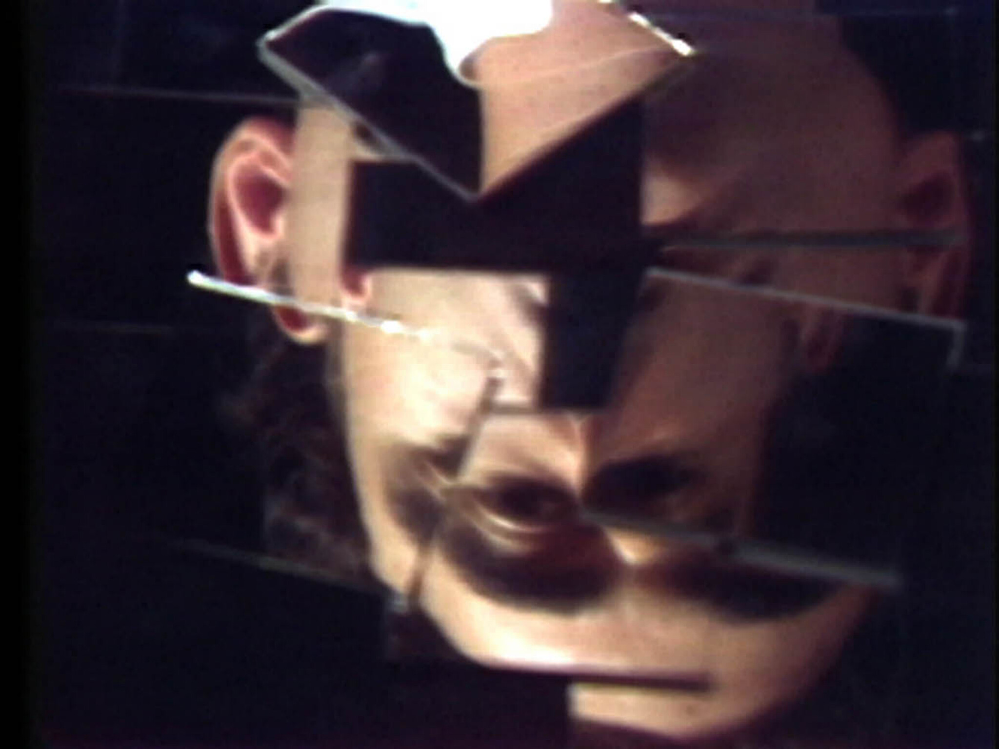 An upside-down face appears fragmented across broken mirror pieces against a dark background.