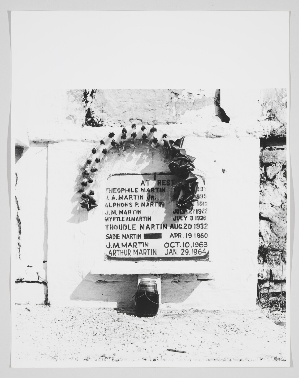 A family tomb plaque reading Martin with a wreath above and an urn placed below.