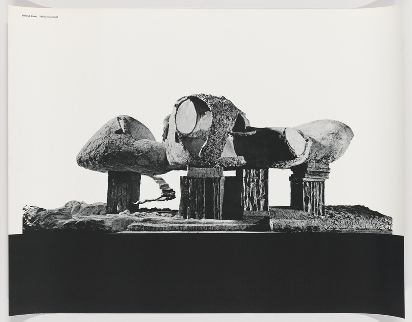 Large abstract stone sculpture with rounded forms rests on columned supports over a dark base.