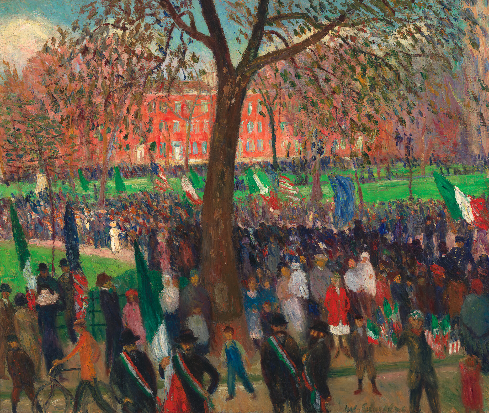 Crowd gathers under a large tree for a flag-filled parade on a green city lawn.