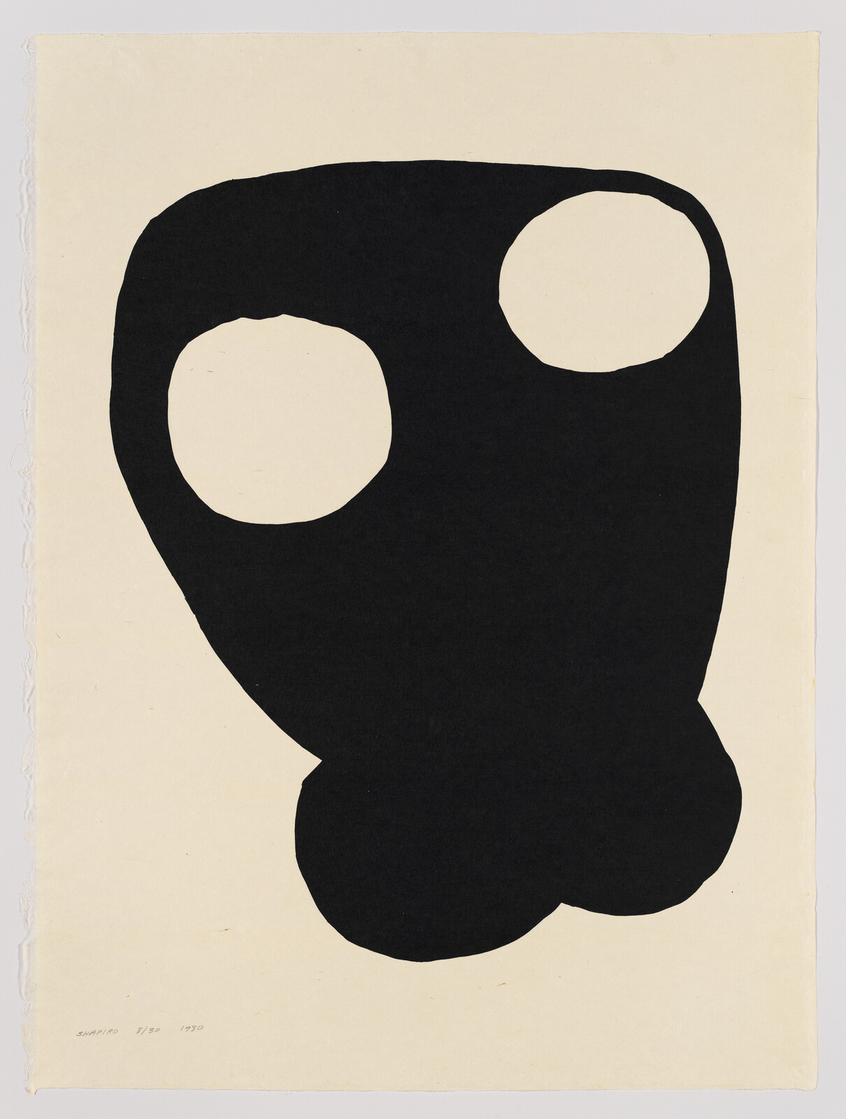 Large black abstract shape with two round cutouts on off-white paper, resembling a simple face or mask.