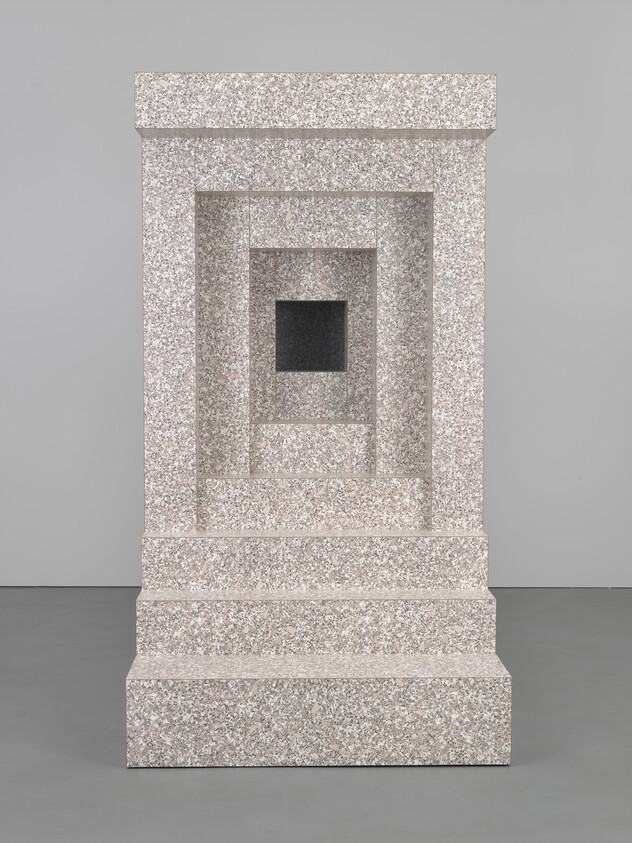 A sculpture resembling a classical architectural column with a series of receding frames, creating a visual tunnel effect, displayed against a plain background. The piece is made of materials with a speckled granite-like appearance, and the innermost frame contains a dark, seemingly empty space.