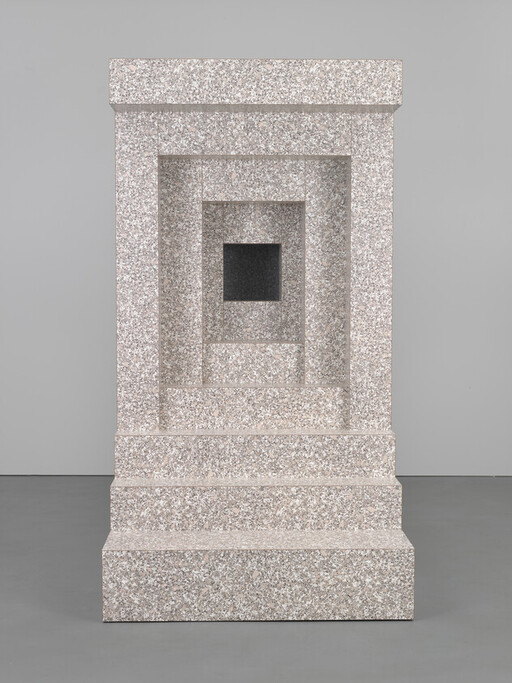 A tall terrazzo stone pedestal with nested rectangular recesses leading to a small dark square opening.