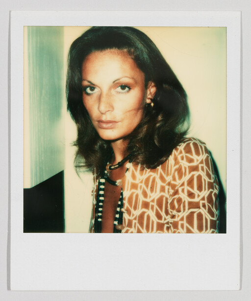 Young woman with patterned shirt and beaded necklace looking directly at the camera.