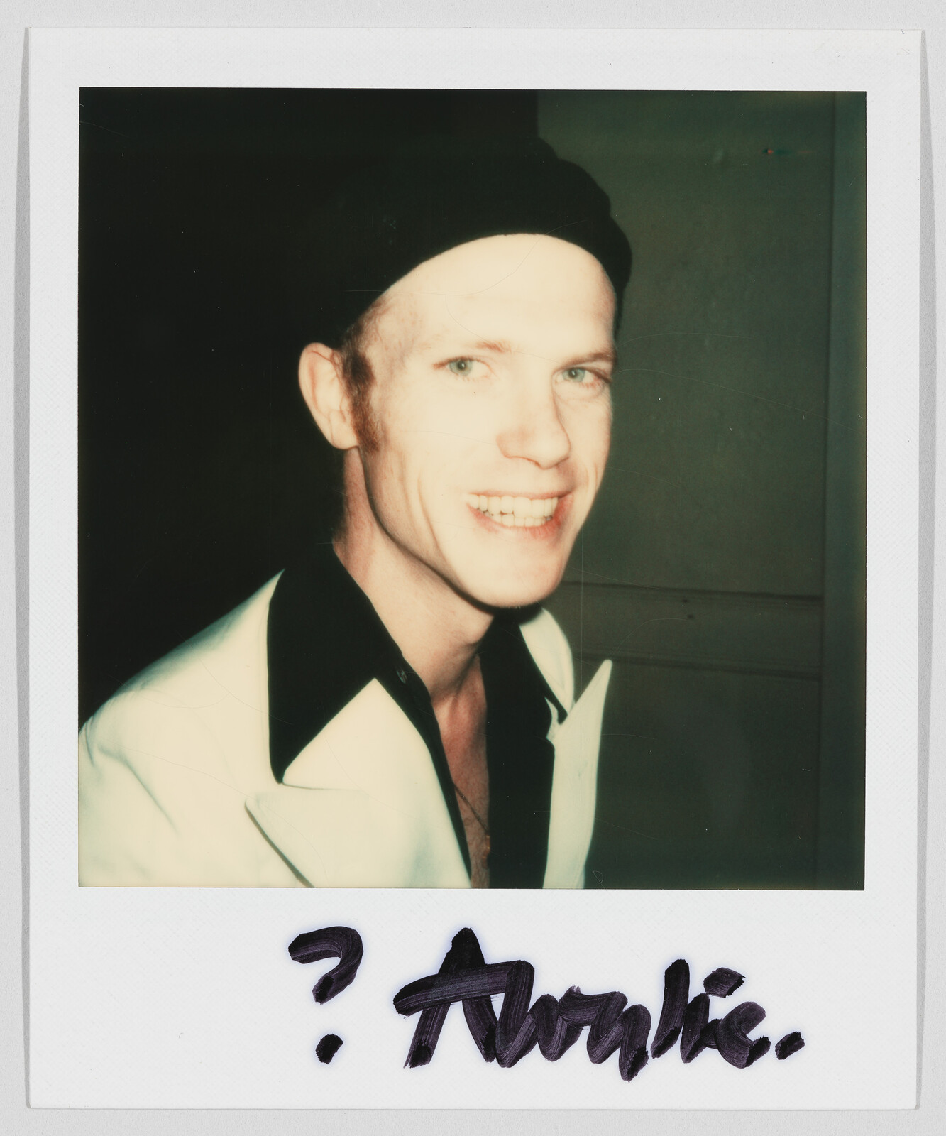 Smiling person wearing a black hat and white jacket; handwritten text below reads "? Archie."