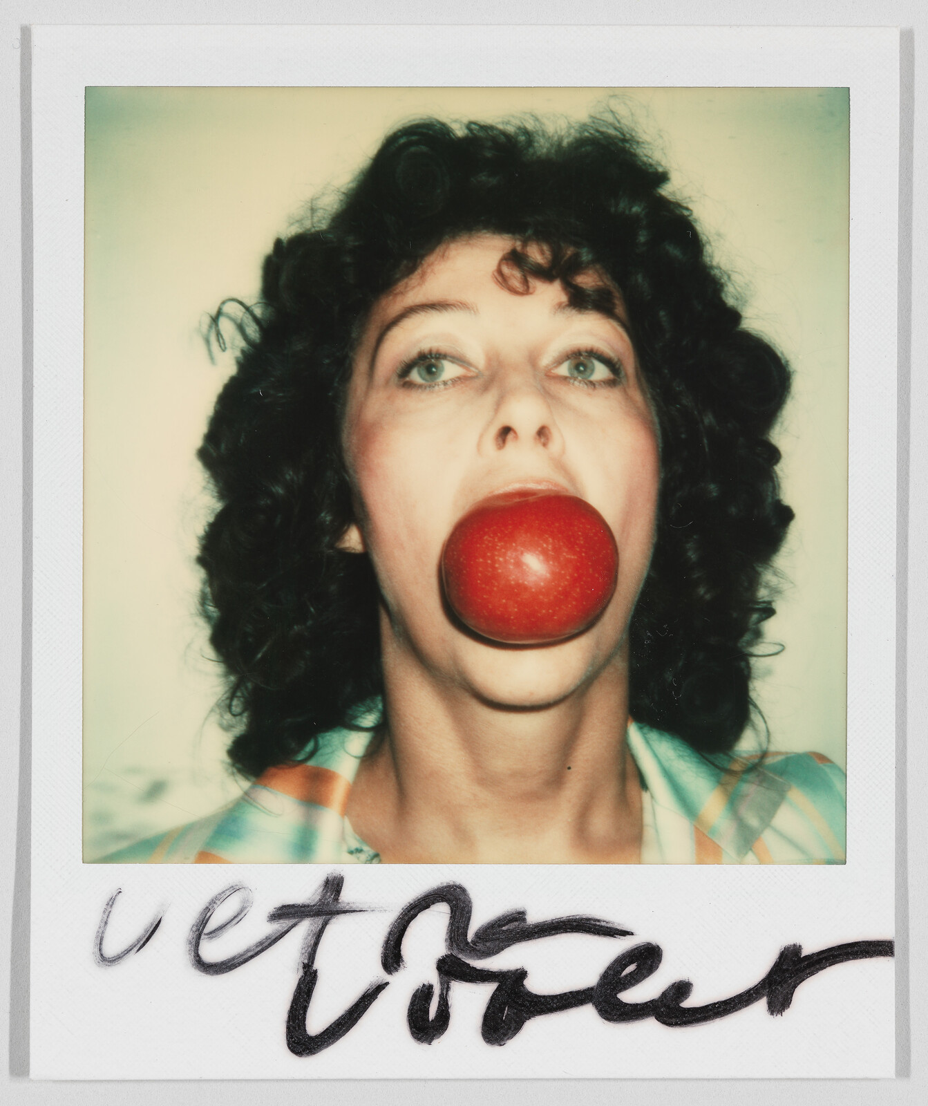 Person with curly hair holds a large red apple in their mouth, handwritten text at the bottom.