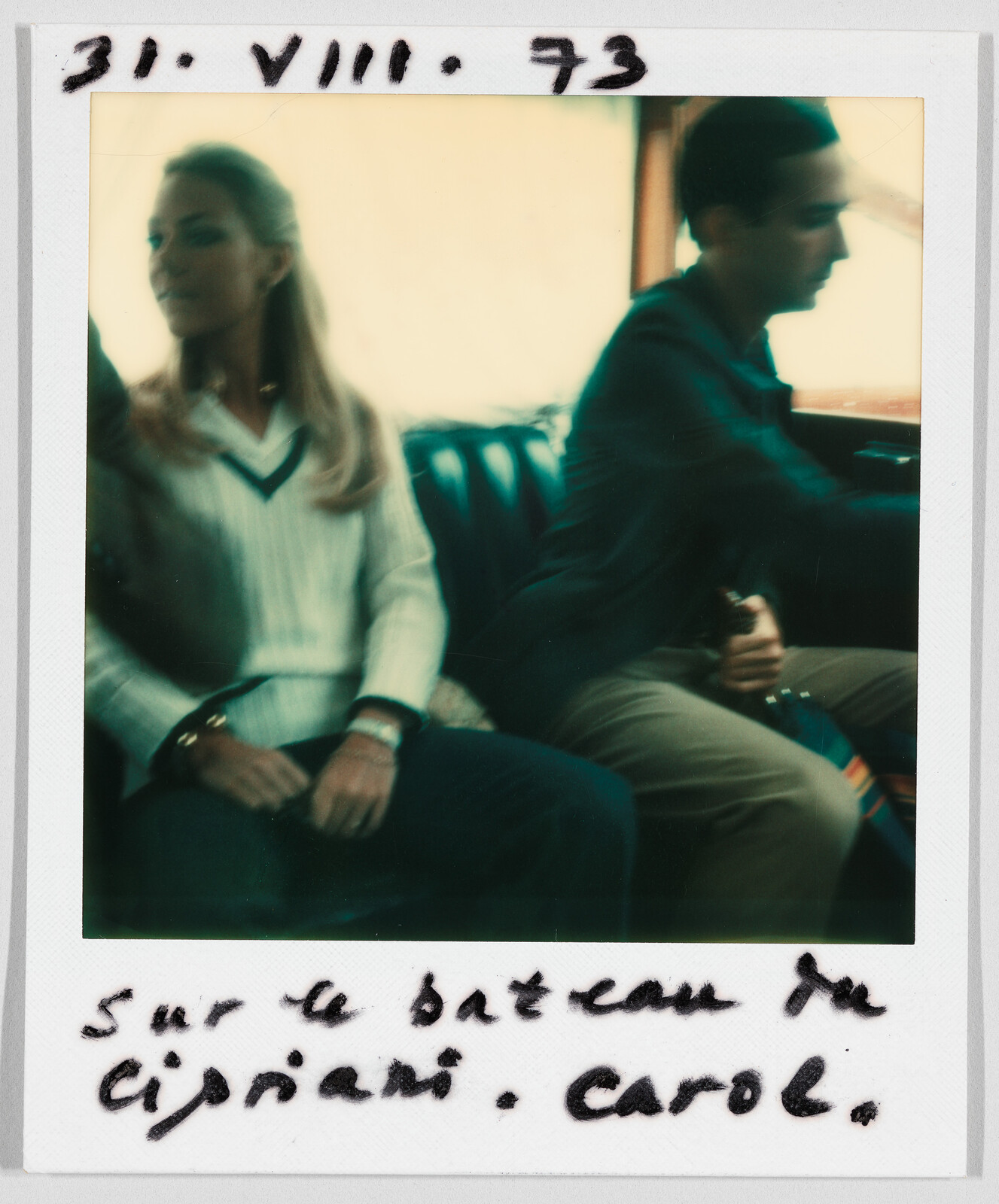 A woman and a man sit together on a boat. Handwritten text reads: "31.VIII.73 Sur le bateau de Cipriani. Carol."