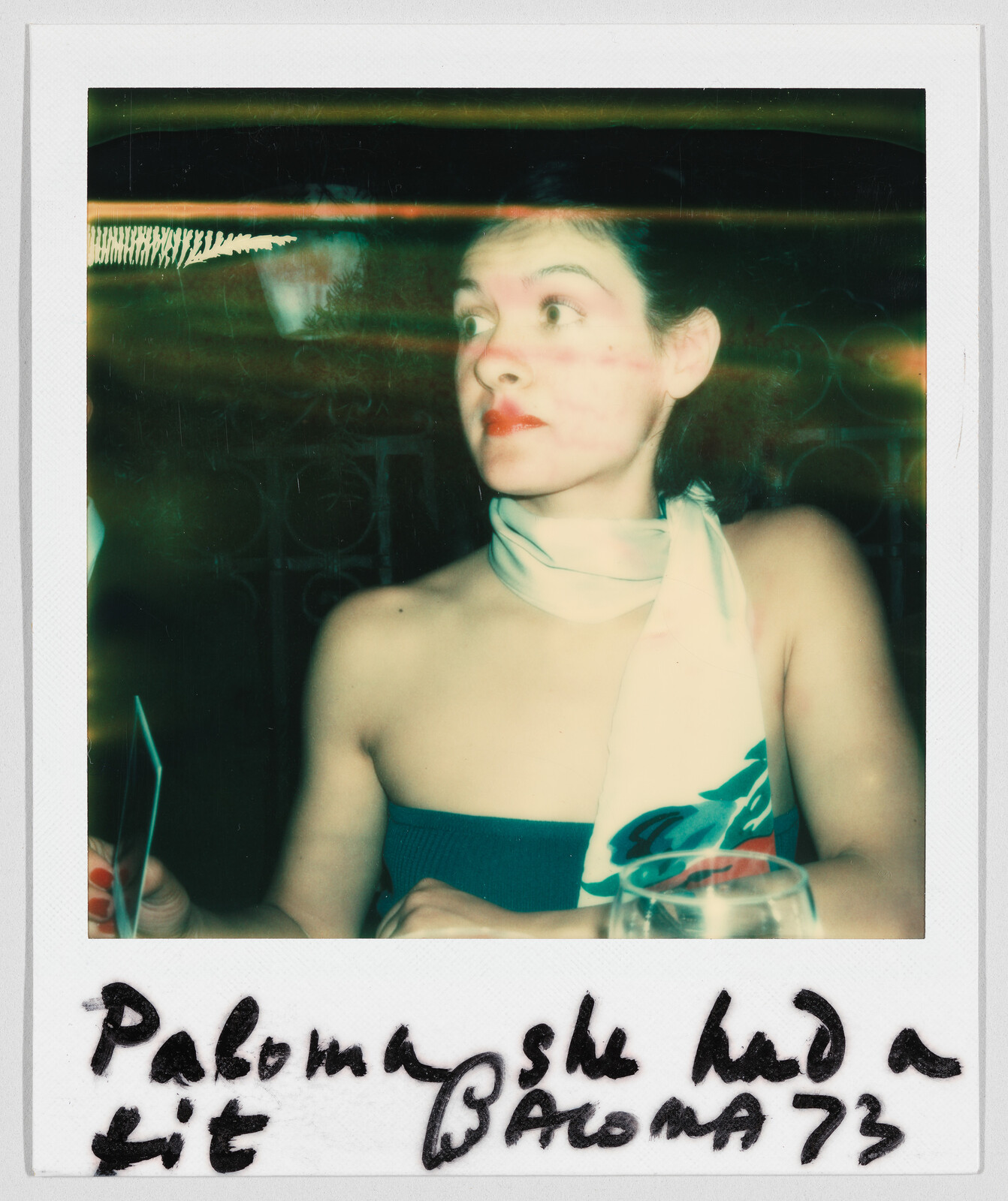 Woman with a scarf around her neck sits at a table; handwritten text below says, "Paloma she had a kit Paloma 73."