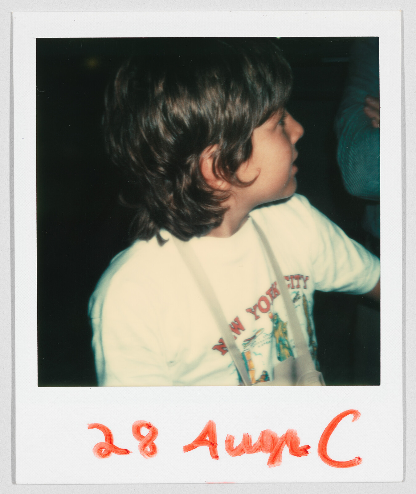 Young child with medium-length hair wearing a “New York City” t-shirt, date “28 Aug” written in red.