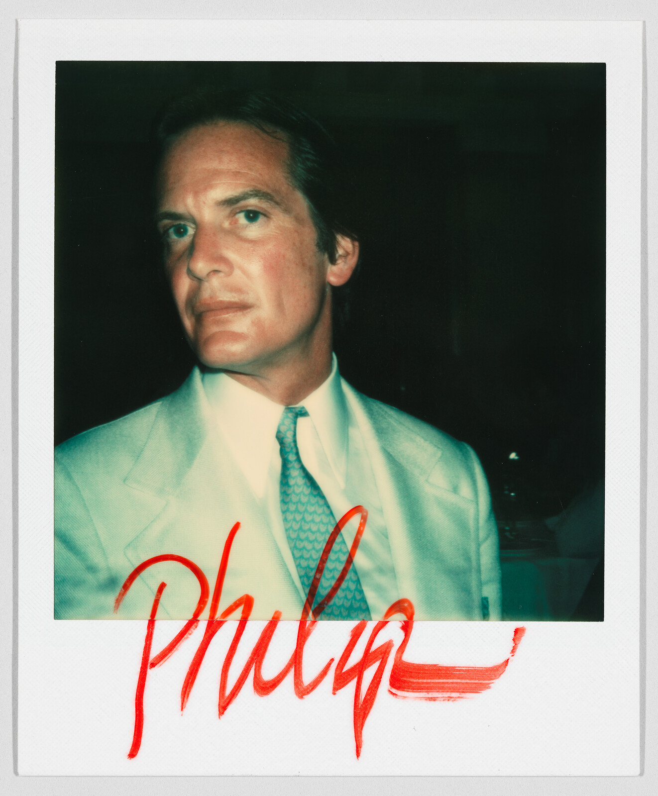 Man in a light suit and tie looking at the camera, with the name "Philip" written in red marker.