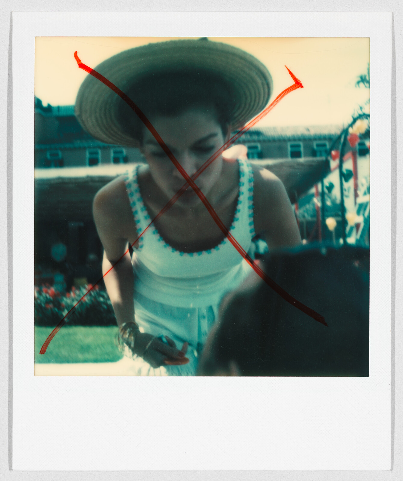 Person wearing a straw hat and white dress, with a large red X drawn over the image.