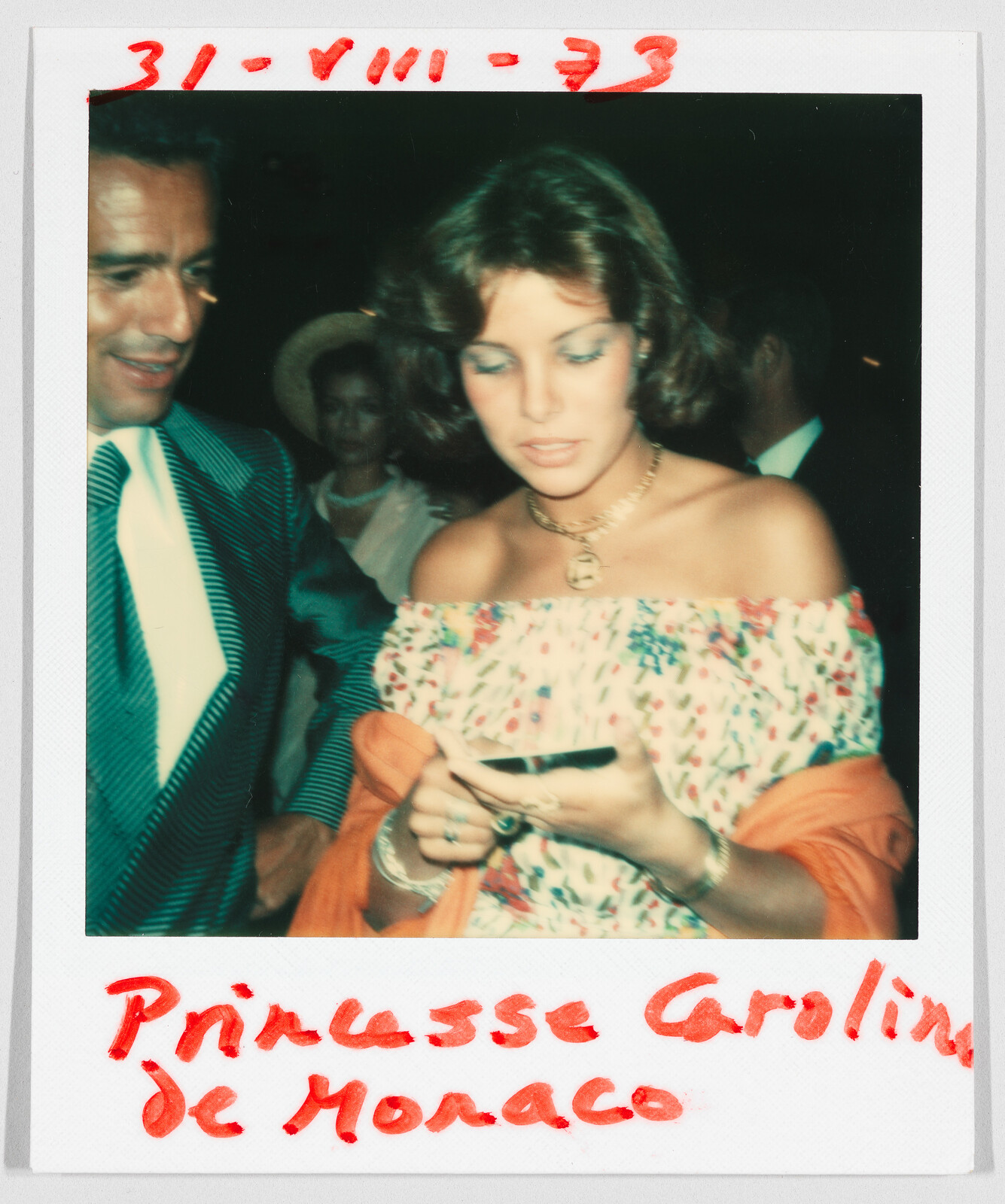 A woman in a floral dress looks down at an object in her hands, with handwritten text: "Princesse Caroline de Monaco."