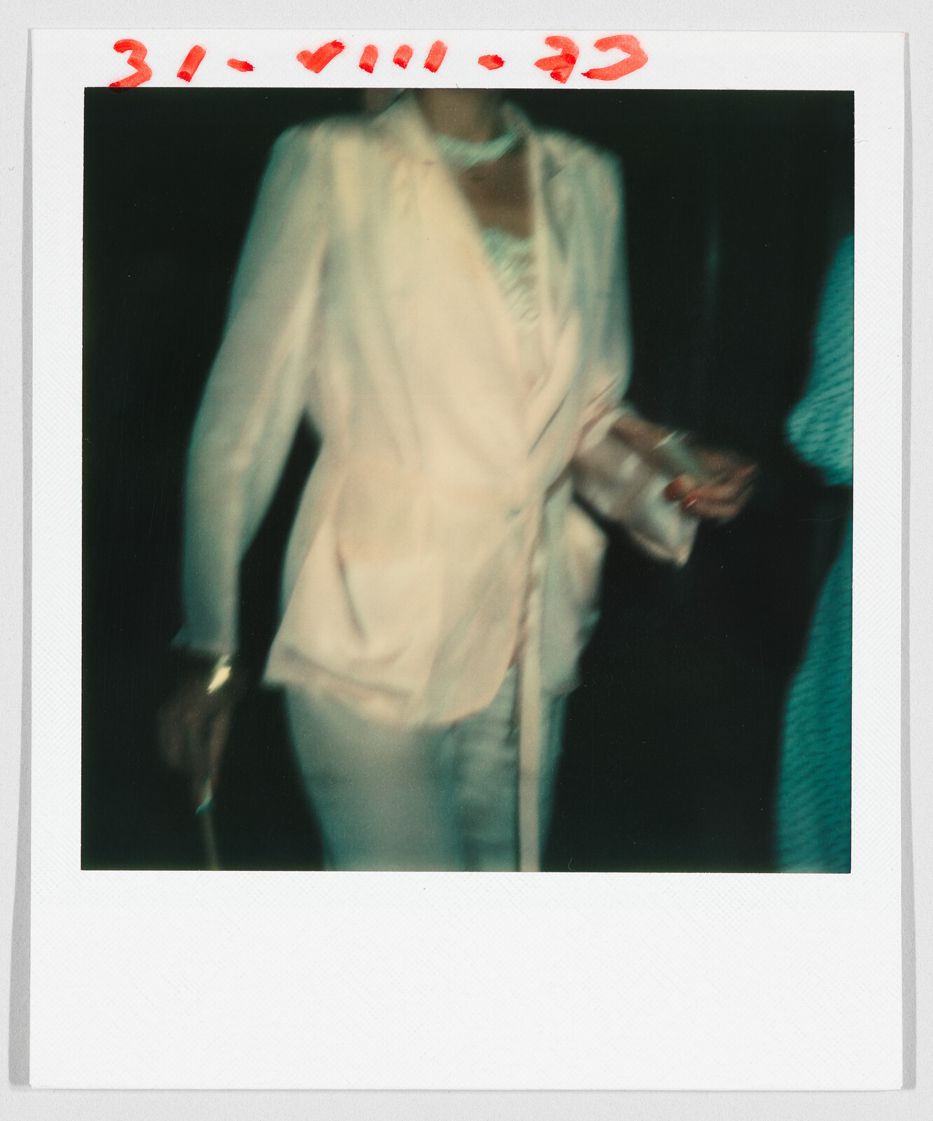 Person wearing a light-colored suit, partially out of frame, with red text “31.VIII.79” written at the top.