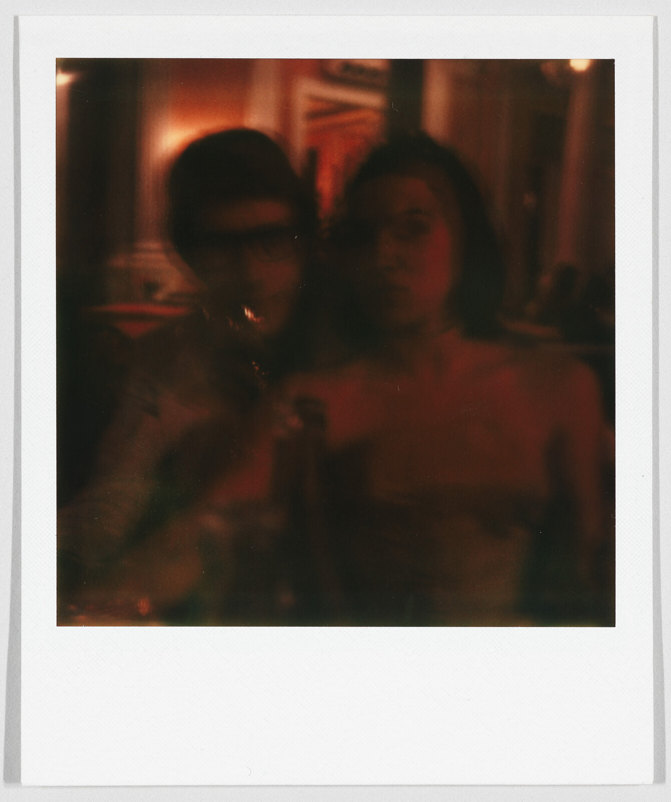 Two people sitting close together in a dimly lit room, their faces are blurry and hard to see.