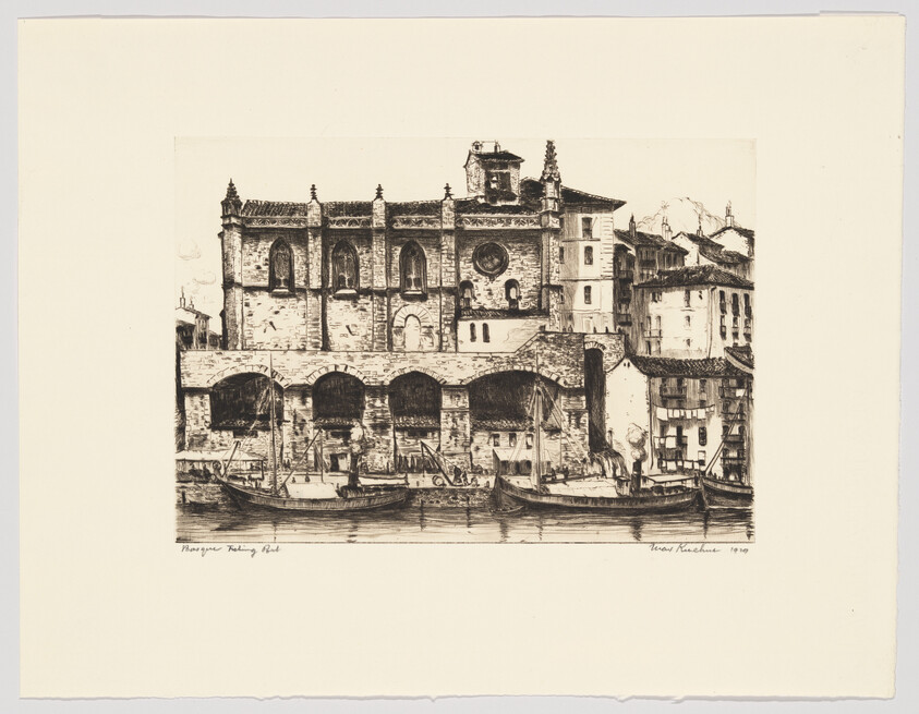 Boats moored along a riverfront in front of a large stone building with arched openings.