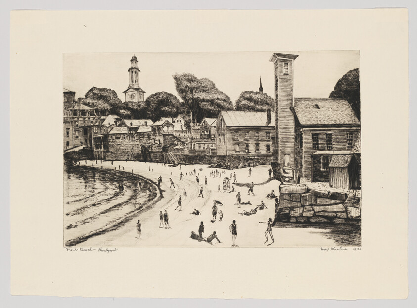 People relax and play on a sandy beach beside a small coastal town with wooden waterfront buildings.