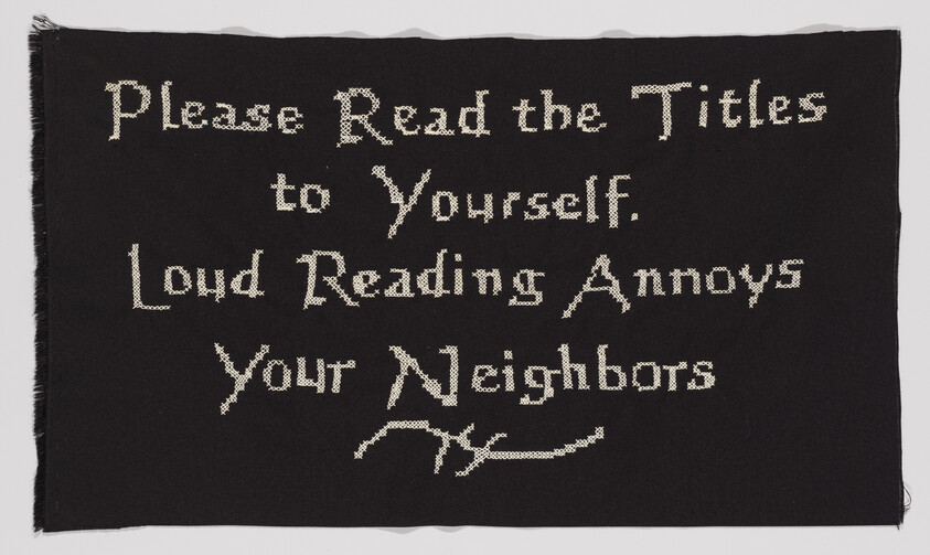 Black cloth sign requests readers to read titles silently because loud reading annoys neighbors.
