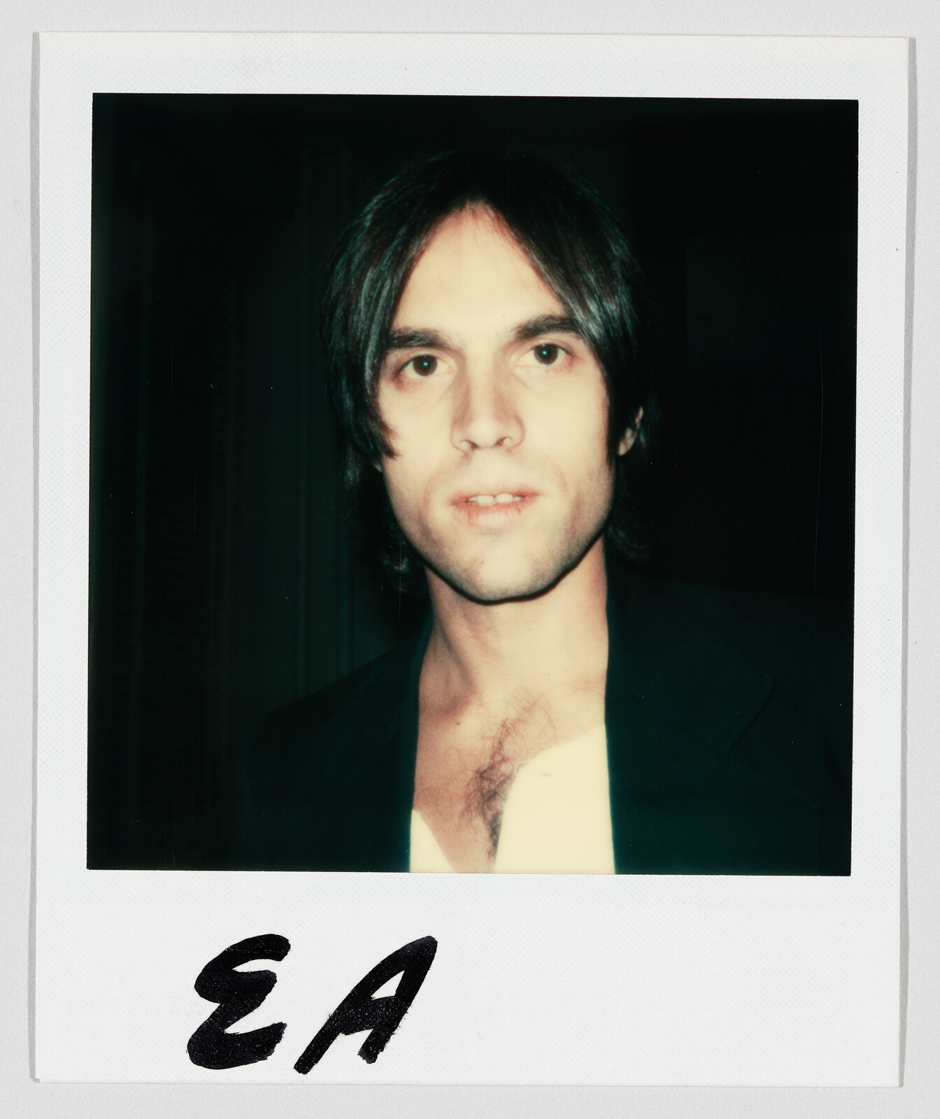 Young person with shoulder-length hair looks at the camera in a Polaroid labeled EA.