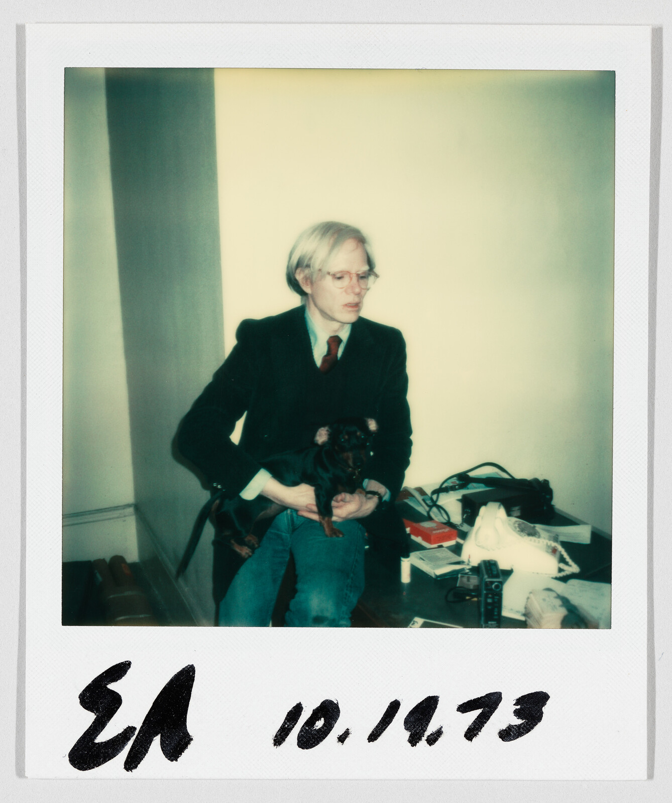 A person with light hair and glasses sits holding a small dog. Handwritten date reads 10.19.73.