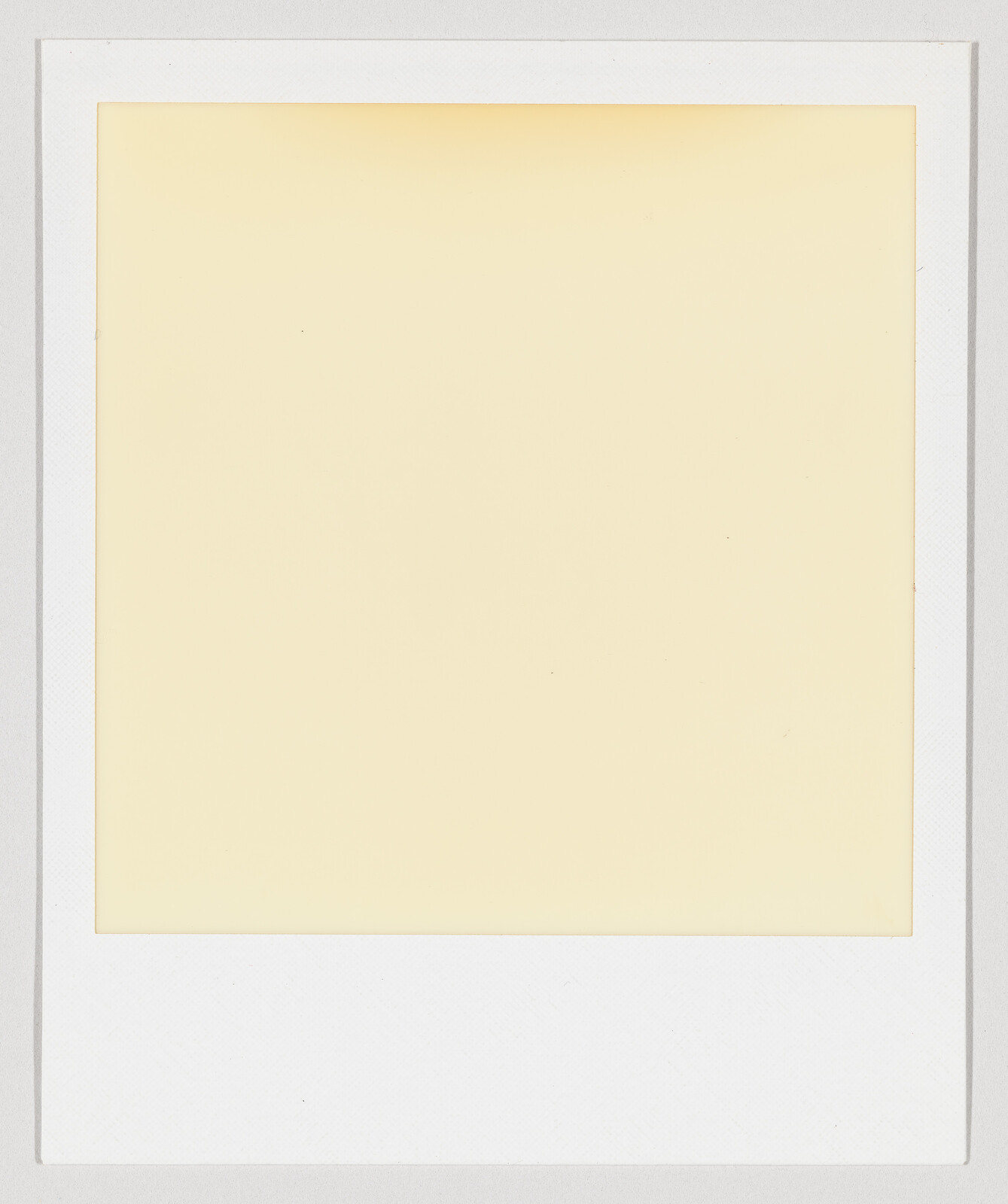 A blank yellowed Polaroid film square with a white border and empty caption area.